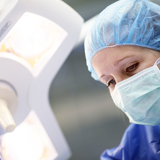 Een persoon die een chirurgische muts en masker draagt.