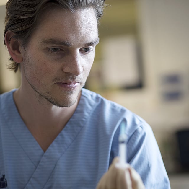 Een persoon in een blauw shirt met een spuit.