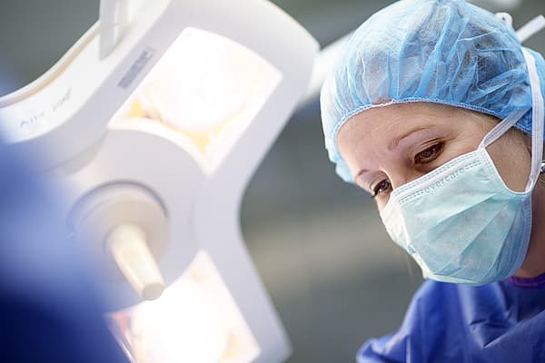 Een persoon die een chirurgische muts en masker draagt.