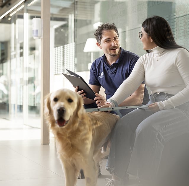 Een persoon en persoon zittend op een bank met een hond.