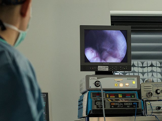 Een persoon in scrubs die een monitor bekijken.