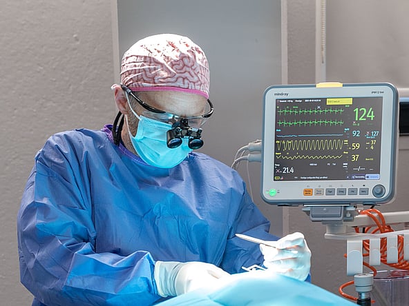 Een persoon die chirurgische uitrusting en handschoenen draagt.